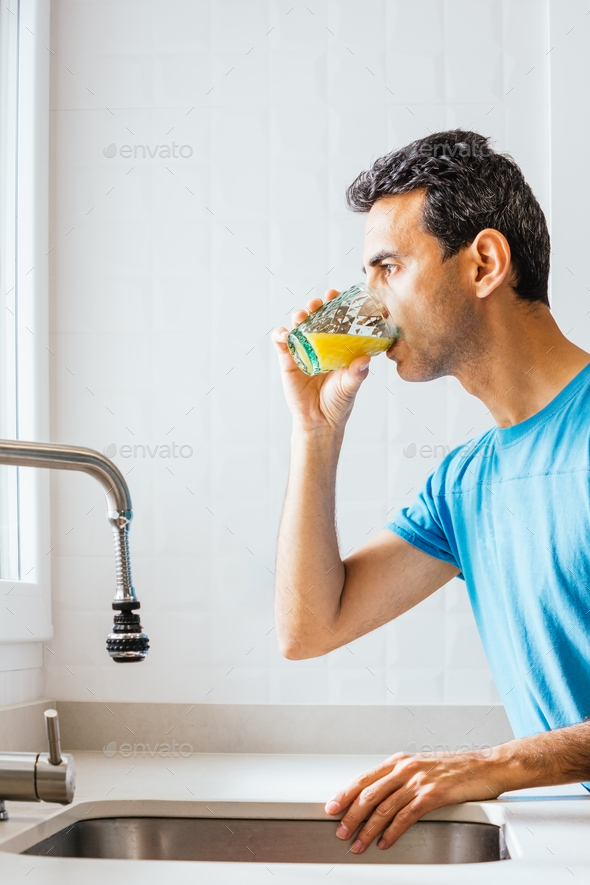 forty year old man drinking a glass of orange juice Stock Photo by alfotomp